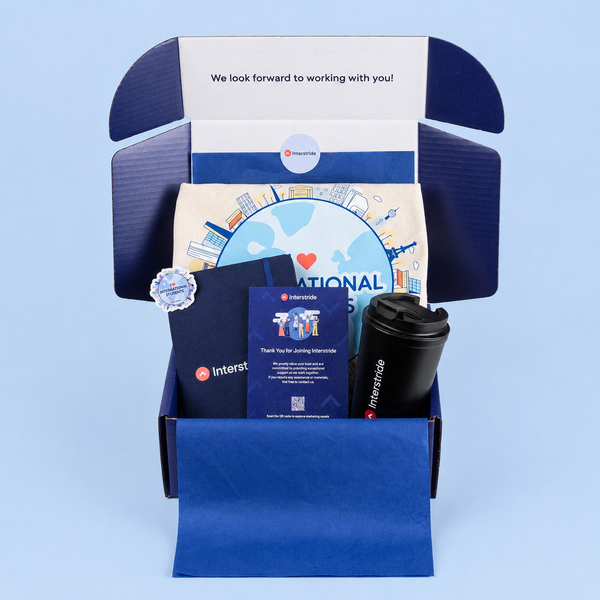 Collection of branded items including a mug, notebook, and promotional materials in a blue box on a light blue background.